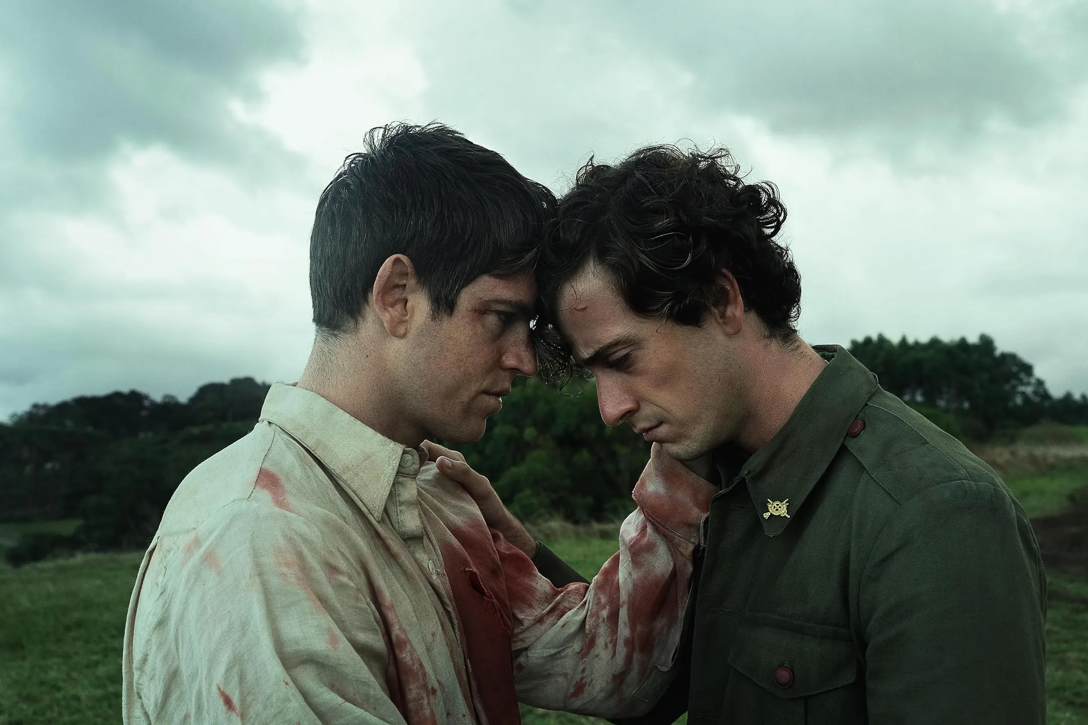 Two men resting their foreheads together in a field, in a scene from La Bola Negra