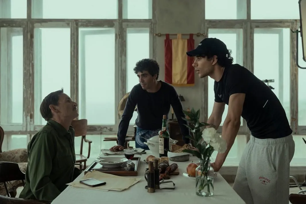 Three men around a table during the filming of La Bola Negra
